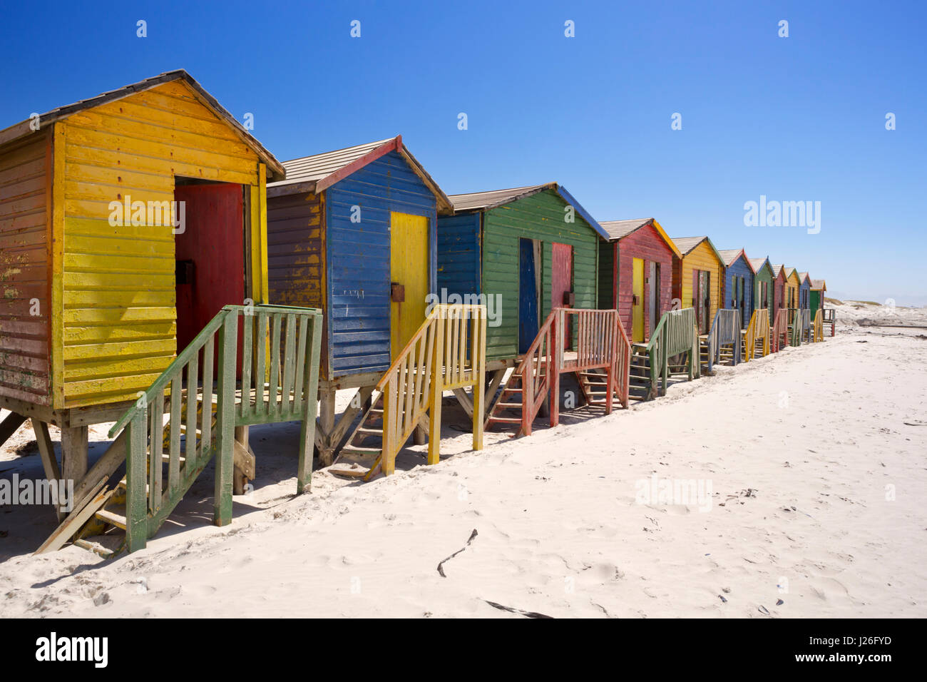 Old colourful beach huts on the beach in Muizenberg, South Africa on a sunny day. Stock Photo