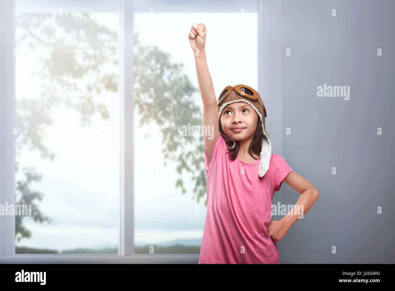 Beautiful asian kid in aviator helmet dreaming of being a pilot at home Stock Photo