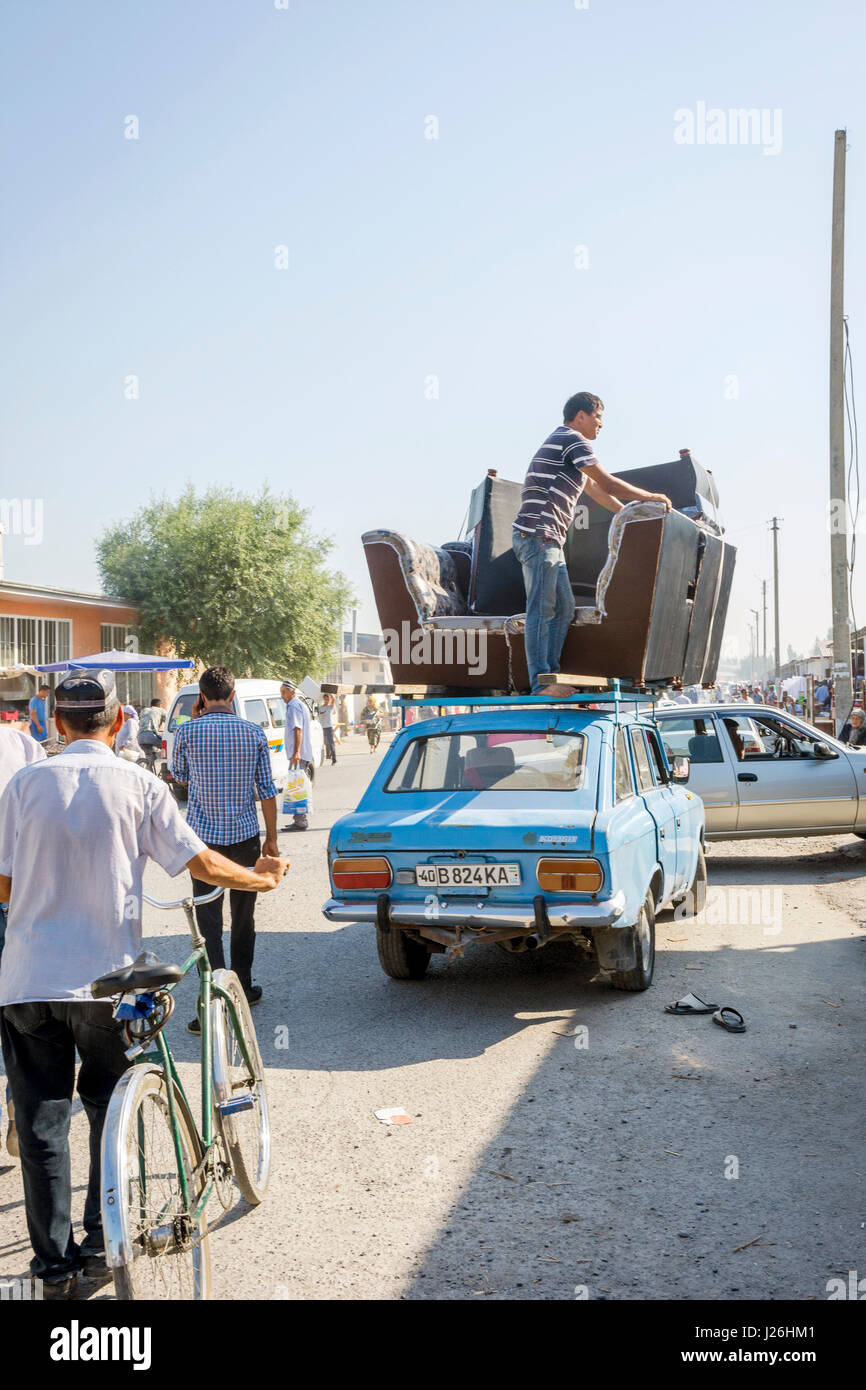 MARGILAN, UZBEKISTAN - AUGUST 21: People transporting sofa on the roof of old soviet Lada car from the Kumtepa bazaar. August 2016 Stock Photo
