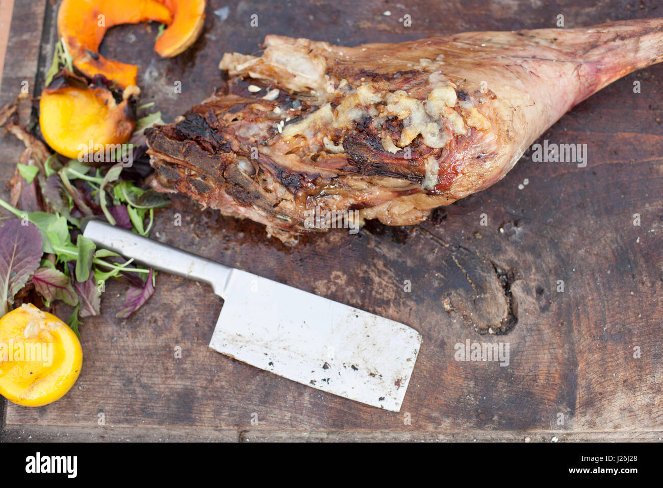 Leg of lamb with pumpkin on a butchers block with a meat cleaver Stock Photo