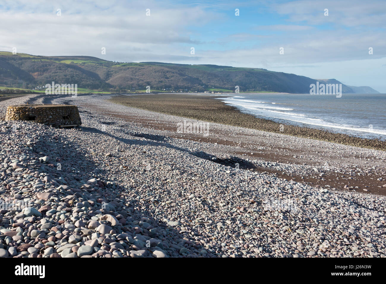 View along the beach in Porlock Bay with Porlock Weir and the hills of Exmoor in the distance. Part of the SW Coast path in Exmoor National Park Stock Photo
