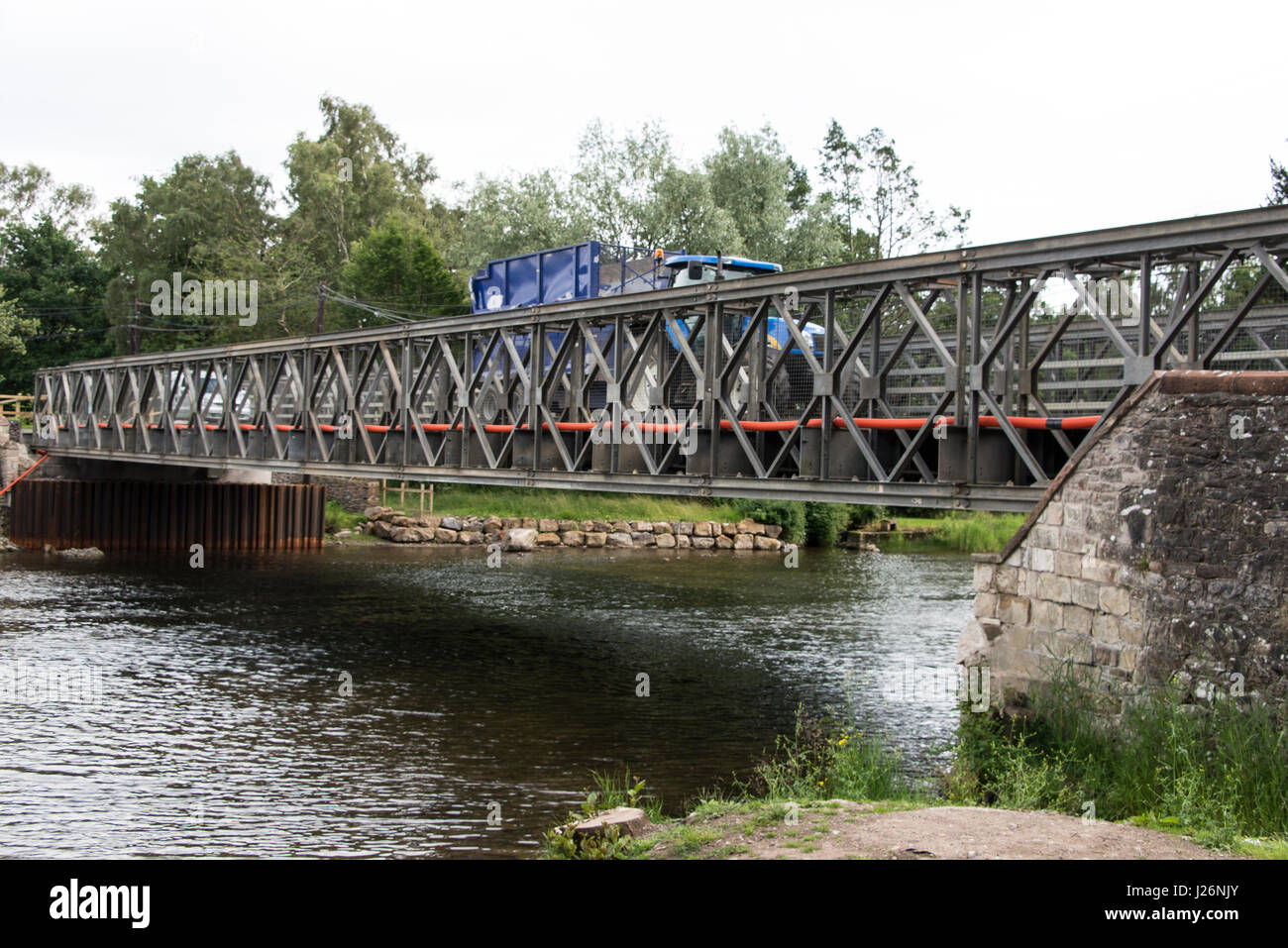 A temporary metal bridge with a green pedestrian walkway at Pooley Bridge, a village  named after the bridge across the River Eamont in the Lake Distr Stock Photo