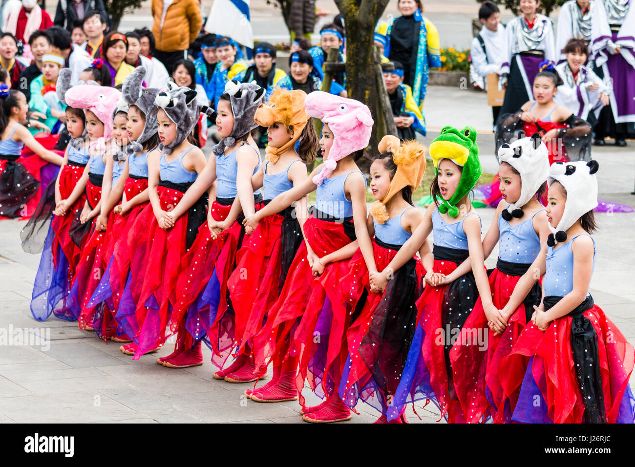 Japan, Kumamoto, Hinokuni Yosakoi Festival. Children's Girl dance team, dressed as fairies in red flayed costumes with animal hats. Dancing outdoors. Stock Photo