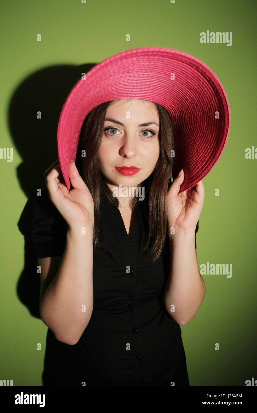 Portrait of a young woman with pink straw hat looking at the camera on ...