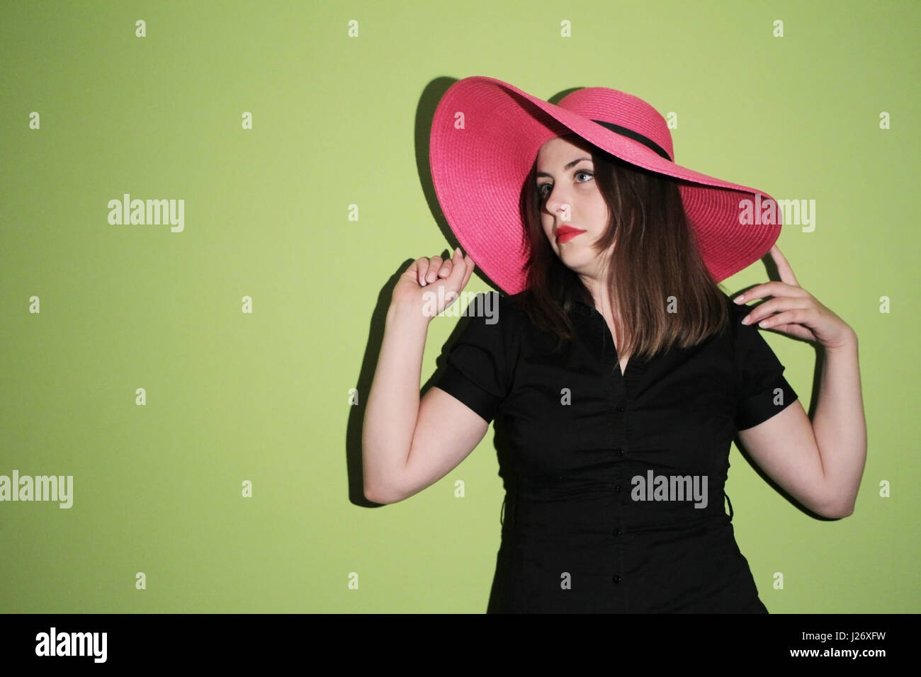 Portrait of a young woman with pink straw hat on green background Stock ...