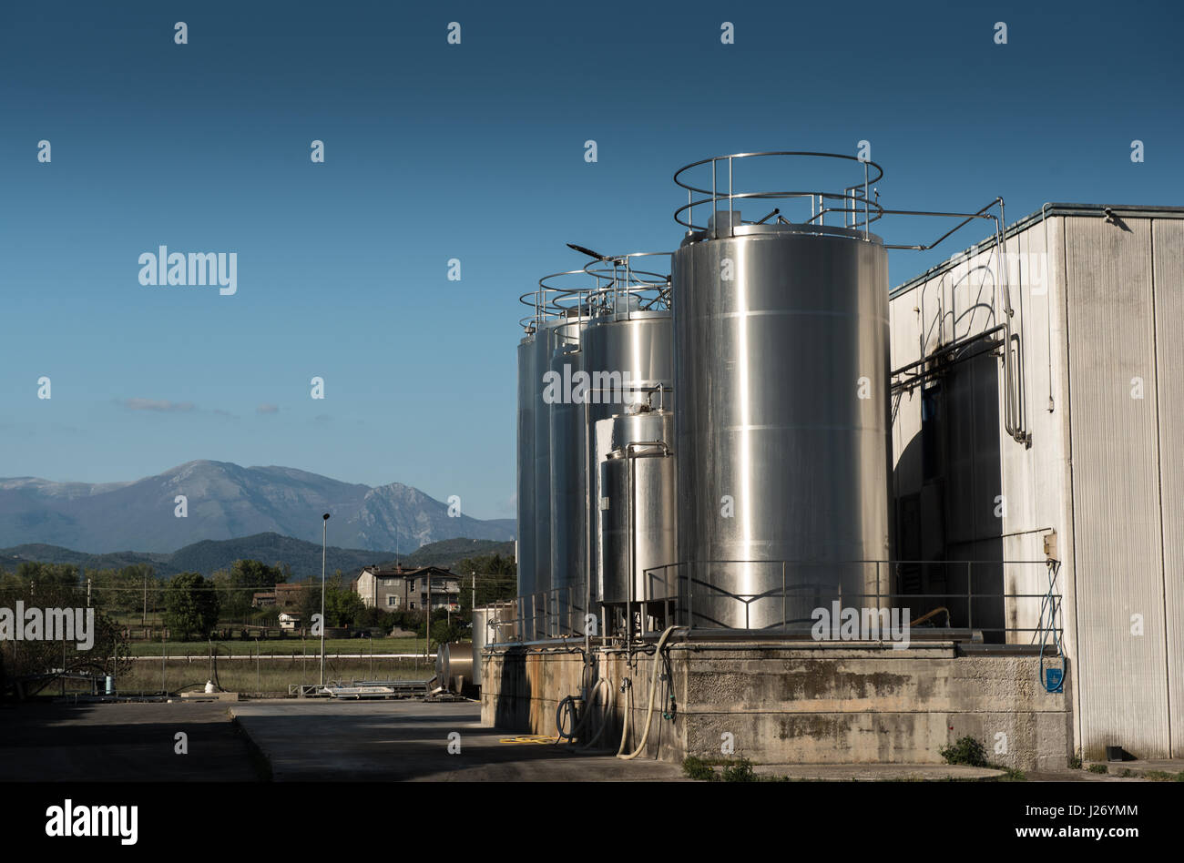 Industrial silos storage structures external view in mountainous location, blue cloudy sky Stock Photo