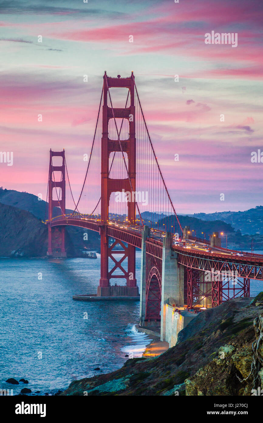 Classic panorama view of famous Golden Gate Bridge seen from scenic Baker Beach in beautiful post sunset twilight with magenta sky and clouds at dusk  Stock Photo