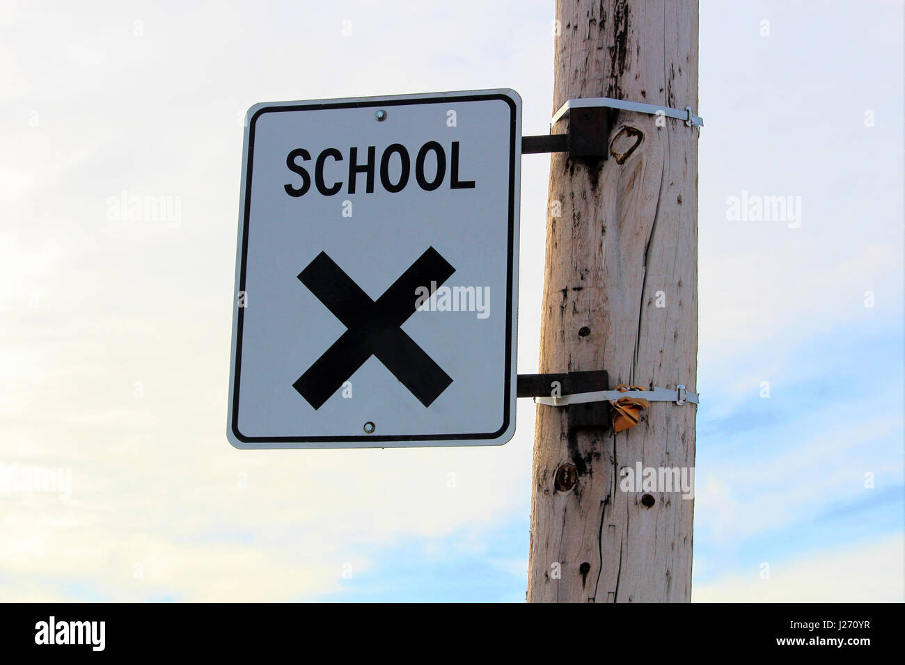 School Crossing Sign on a Power Pole with Cloudy Sky Background Stock Photo