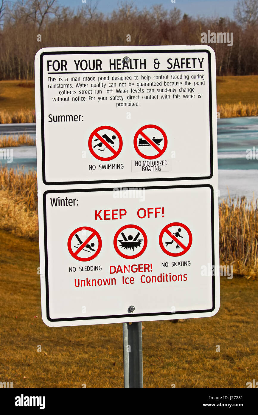 Warning signs around storm drainage pond. Stock Photo