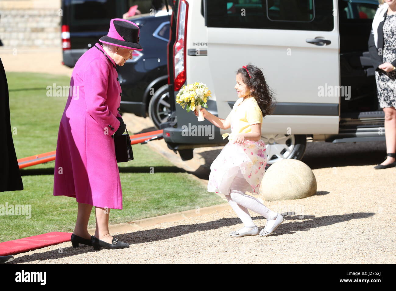Seven year old Dina Rayburn presents Queen Elizabeth II with flowers during a ceremony at Windsor Castle to celebrate the 40th anniversary of Motability. Stock Photo