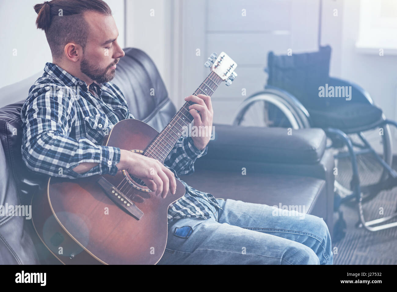 Skilled young handicap playing guitar indoors Stock Photo