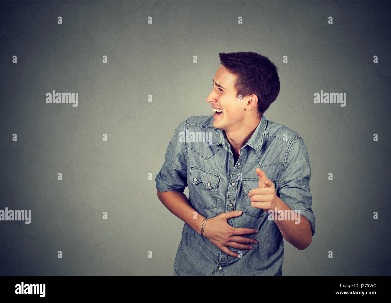 Laughing young man pointing with finger Stock Photo