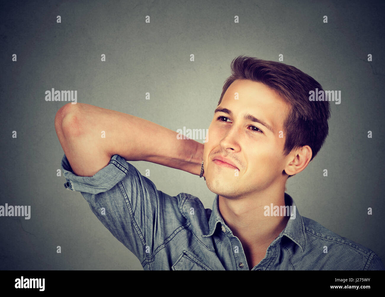 Happy young man thinking daydreaming looking up isolated on gray wall background Stock Photo