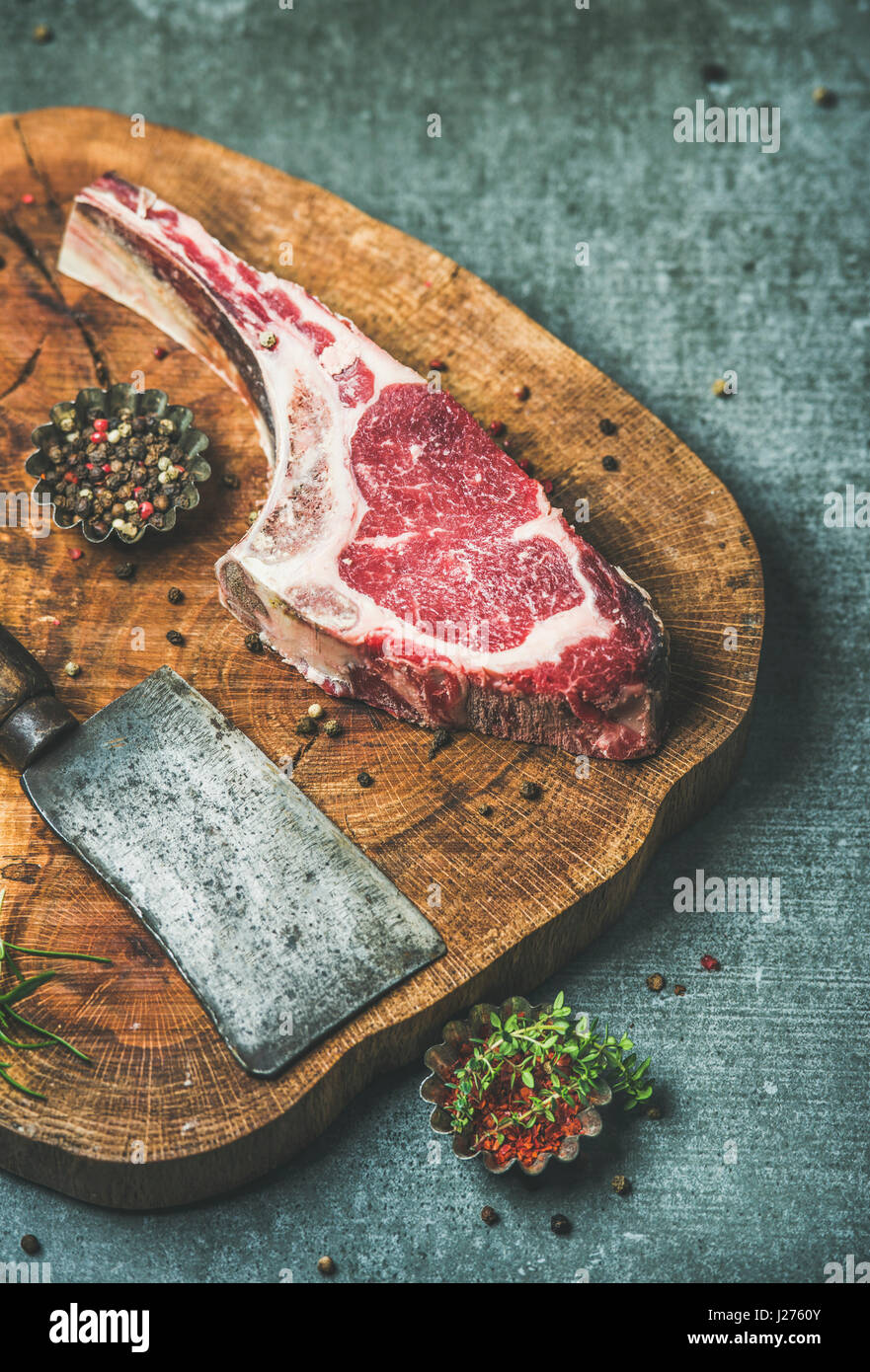 Dry aged raw beef rib eye steak with bone, butcher meat chopping knife