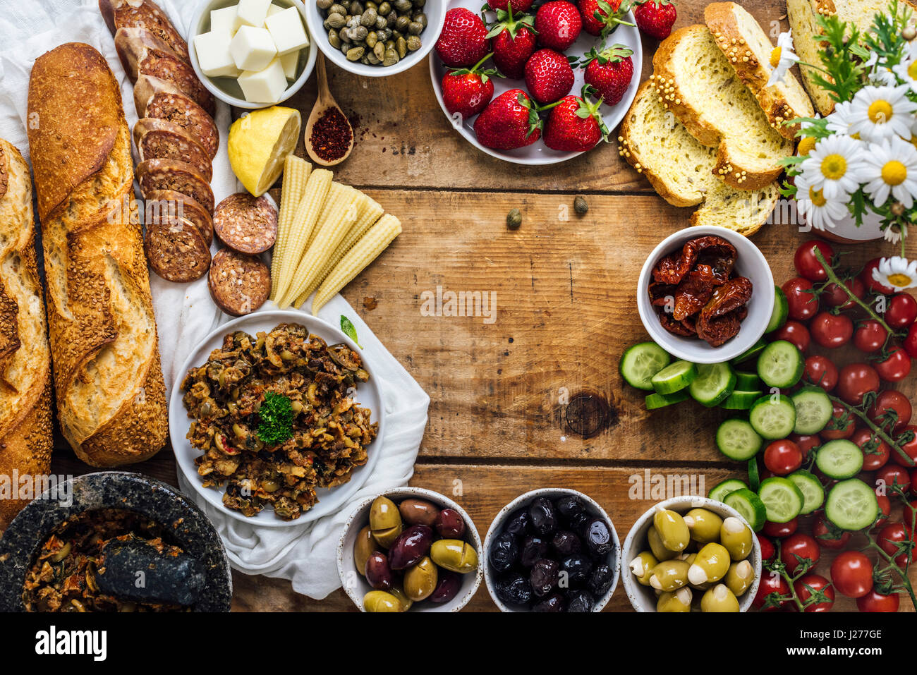 Olive tapenade, sausages, baby corns, french baguette, cheese, capers, strawberries, corn bread slices, sun-dried tomatoes, cherry tomatoes and cucumb Stock Photo