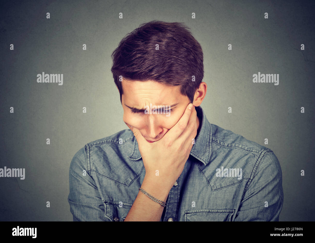 portrait stressed sad young man looking down isolated on gray wall ...