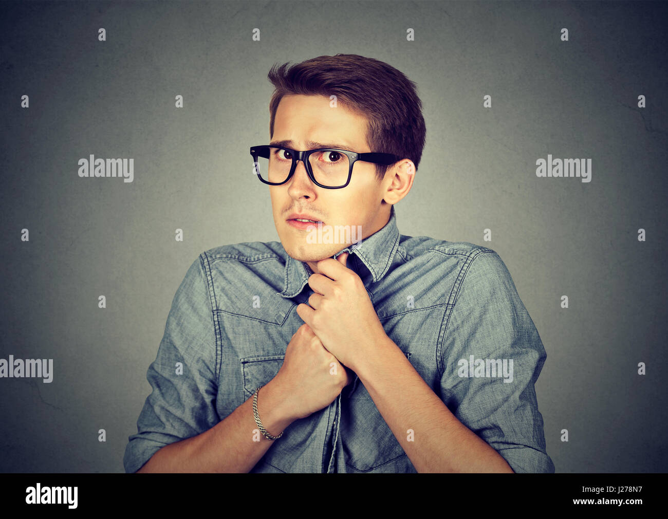 Nervous stressed young man student feels awkward looking at camera anxiously craving something isolated gray wall background. Human emotion face expre Stock Photo