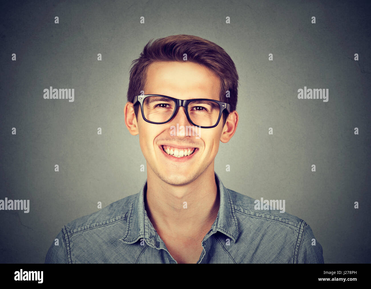 Young handsome man with great smile wearing fashion eyeglasses isolated on gray wall background Stock Photo