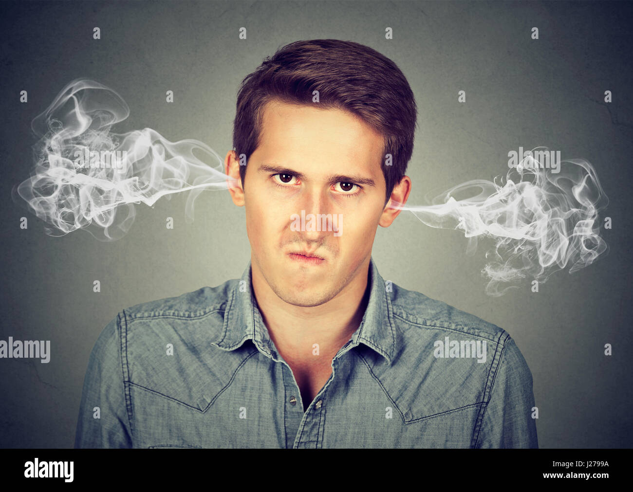 Closeup portrait of angry young man, blowing steam coming out of ears, about to have nervous breakdown isolated gray background. Negative human emotio Stock Photo