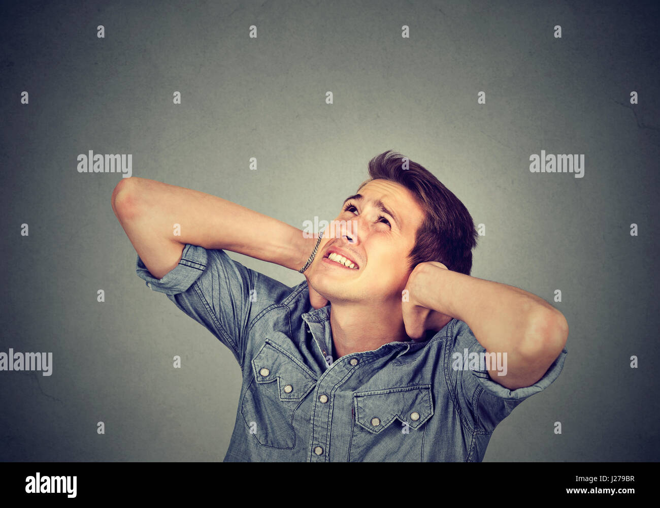Portrait young annoyed, unhappy, stressed man covering his ears