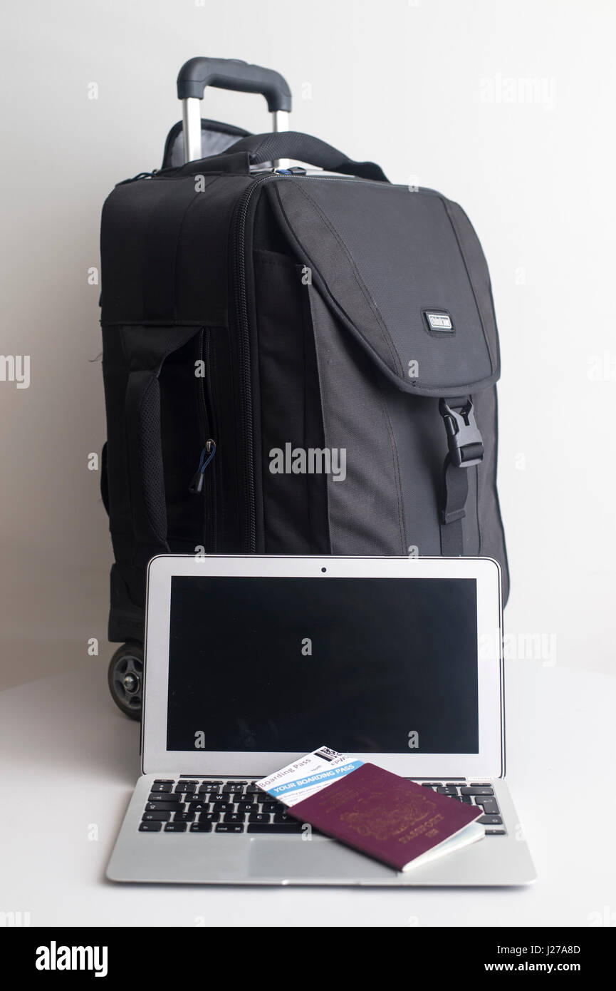 A Passport Flight Boarding Pass And Laptop Next To A Suitcase