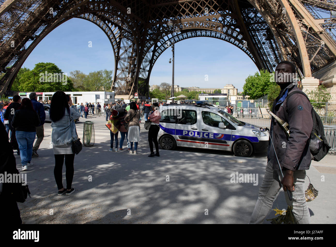 French police car monitoring the area around the Eiffel Tower in Paris, France; Street vendor selling small Eiffel Tower souvenirs Stock Photo