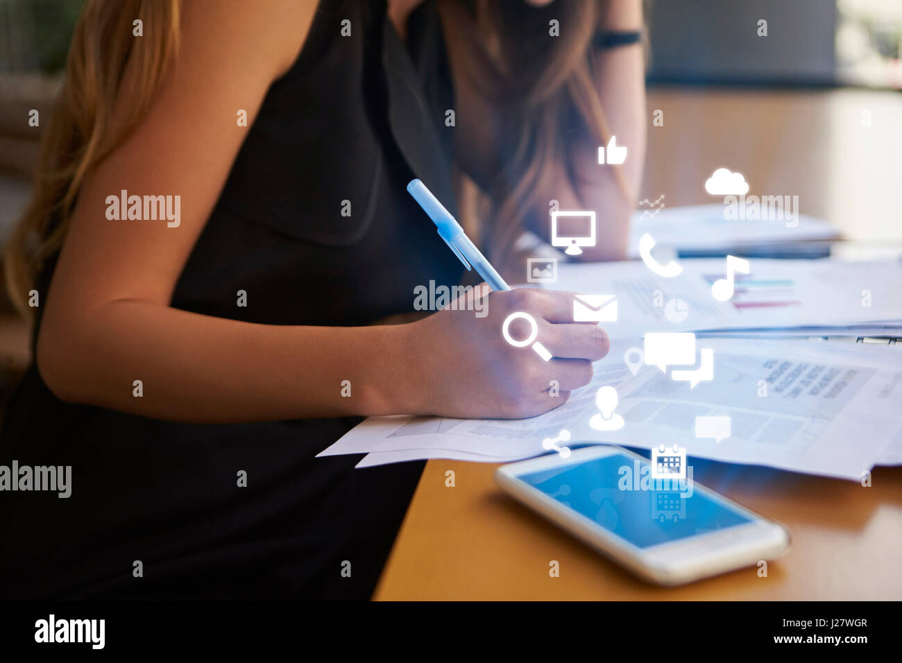 Businesswoman working an office with mobile app icons Stock Photo