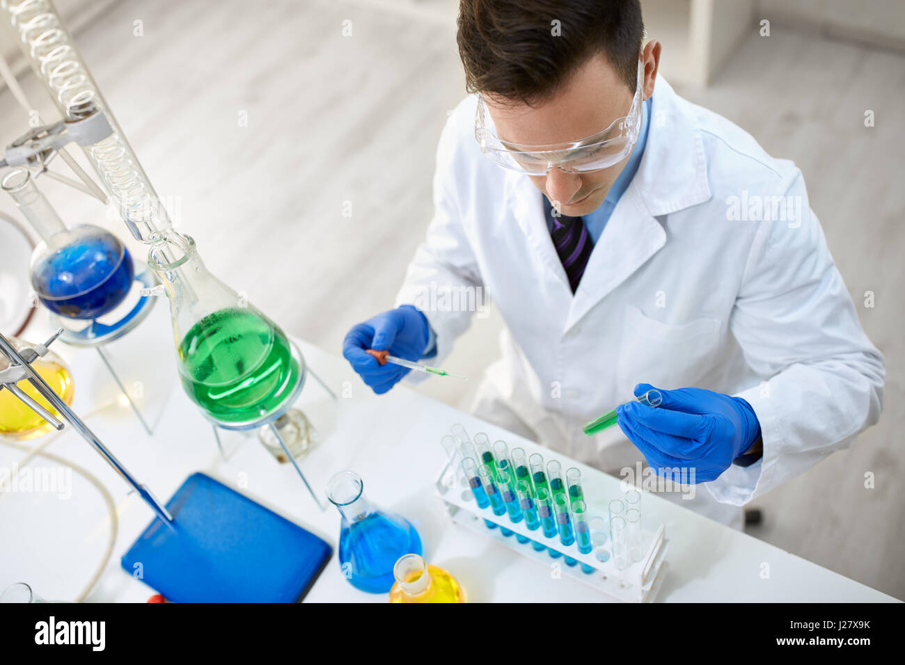 Male scientist carrying protective glasses doing experiment with test tube Stock Photo