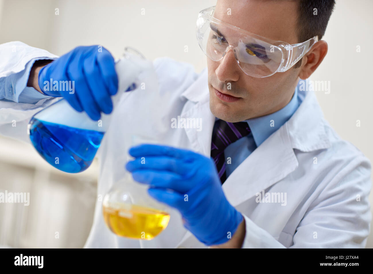 close up of young male scientist with flask making test or research in chemical laboratory Stock Photo