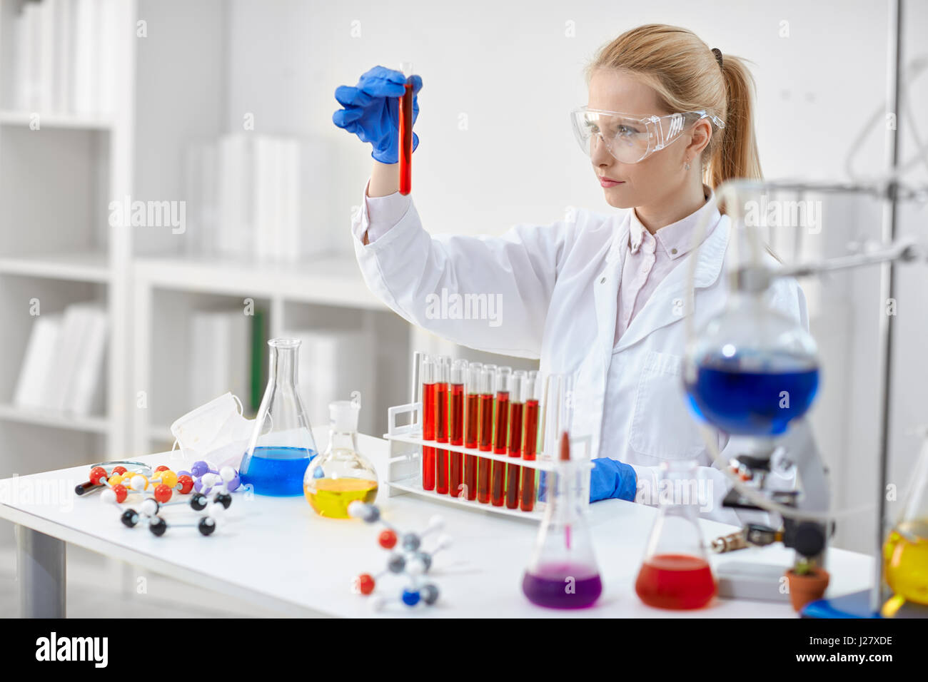 woman in laboratory checking test tubes with red liquid Stock Photo
