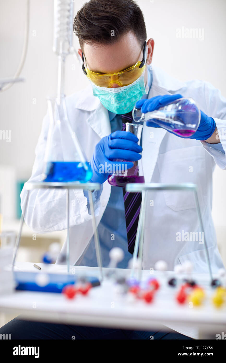Scientist pouring liquid from beaker in chemistry lab Stock Photo Alamy