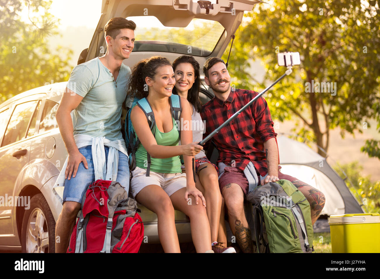 Group of young friends in countryside on camping trip taking selfie using smartphone Stock Photo