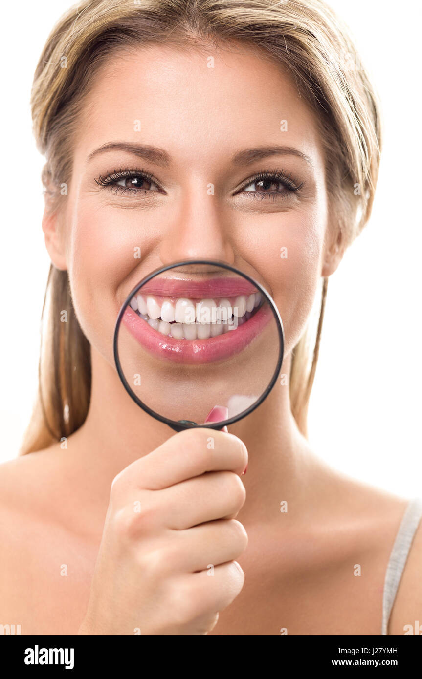 Smiling girl with perfect teeth behind magnifying glass Stock Photo