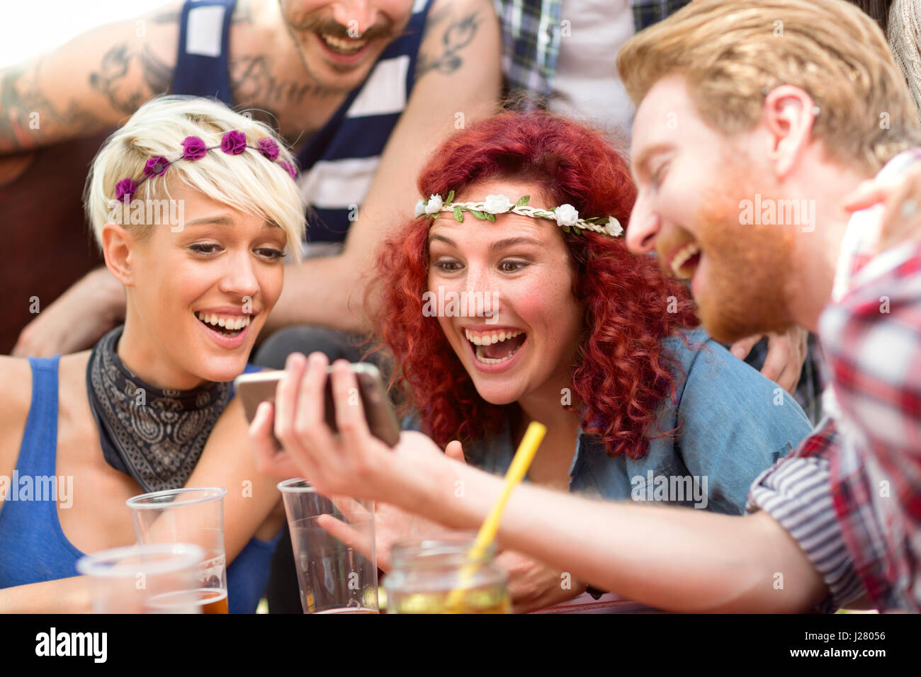 Curly ginger girl is delighted with photos on fellows mobile phone in restaurant in open Stock Photo