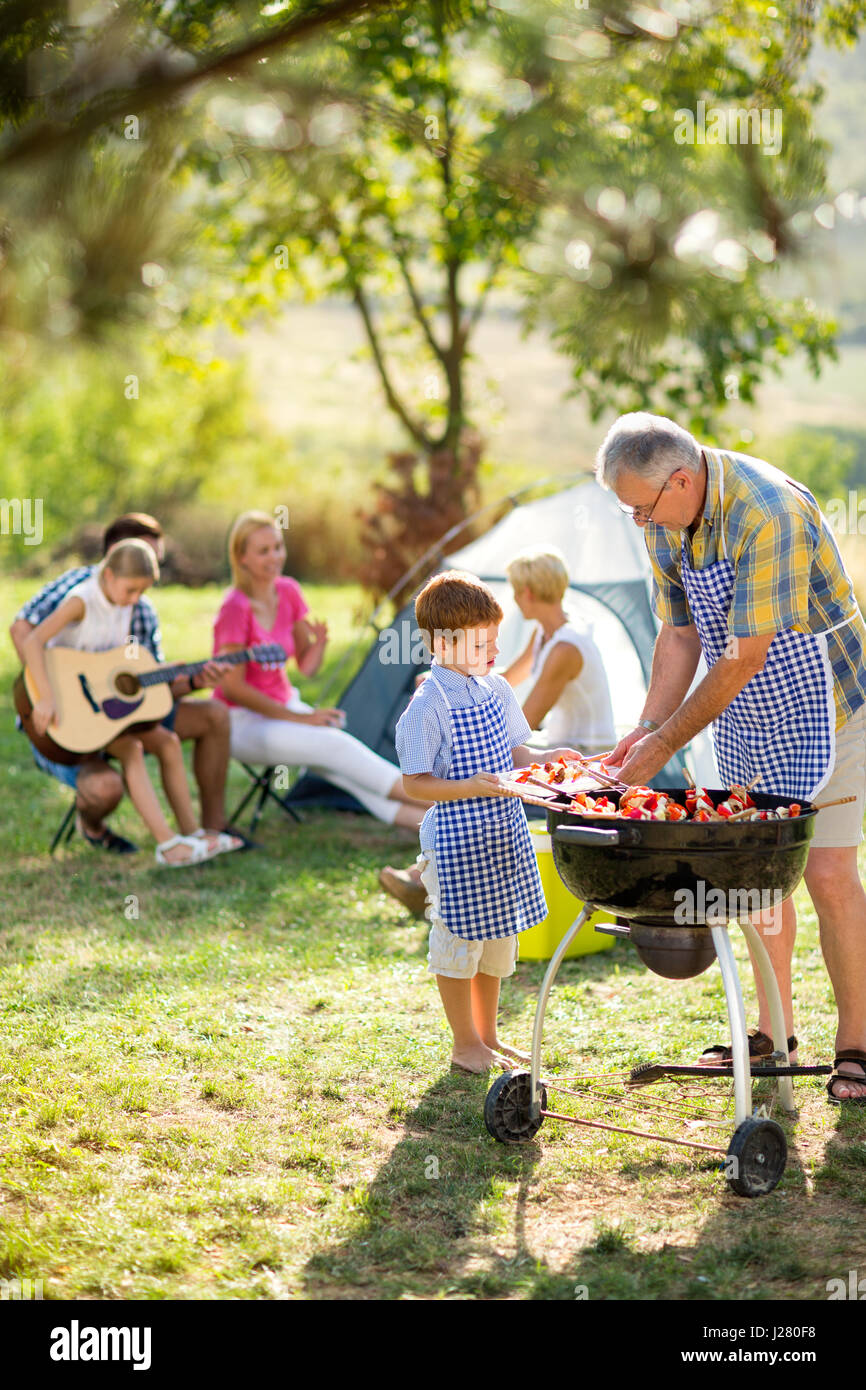 Generation family at barbecue grill on camping Stock Photo Alamy