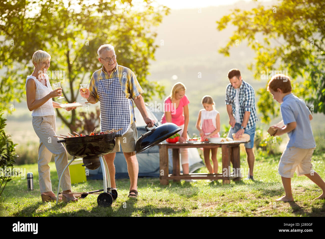 Happy family camping and cooking bbq Stock Photo Alamy