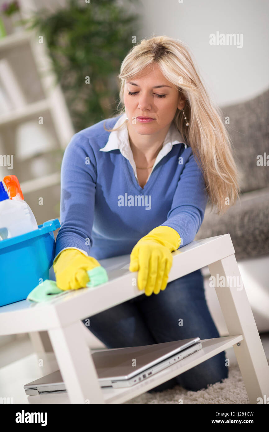Young blond woman cleans table with rag Stock Photo