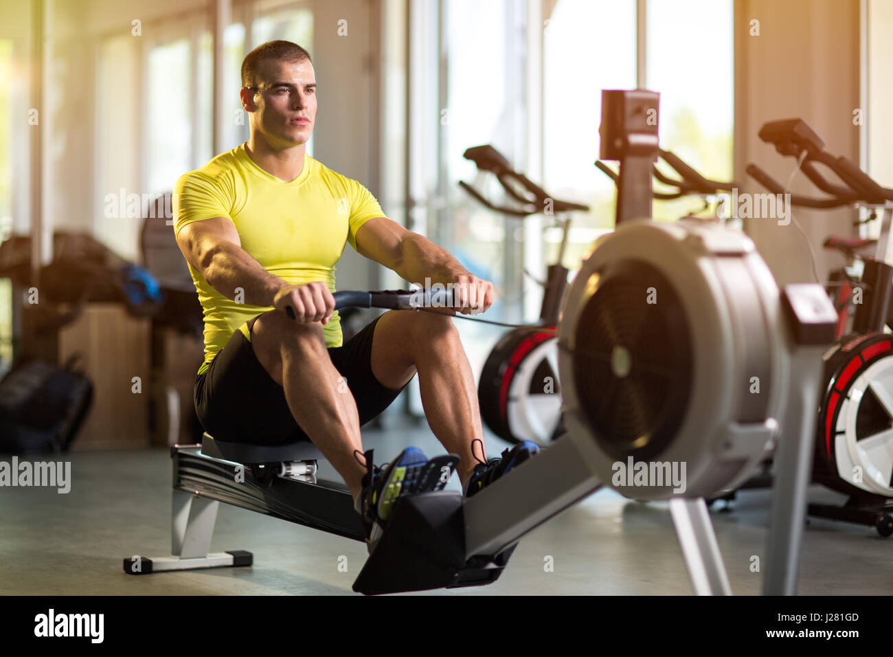 Sporty man exercising in gym on row machine Stock Photo