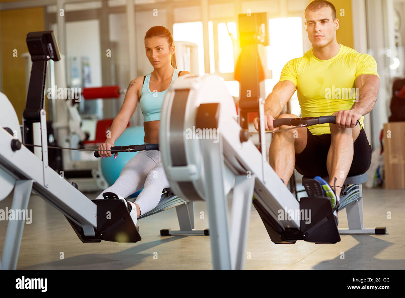 Couple at gym exercising on row machine Stock Photo - Alamy