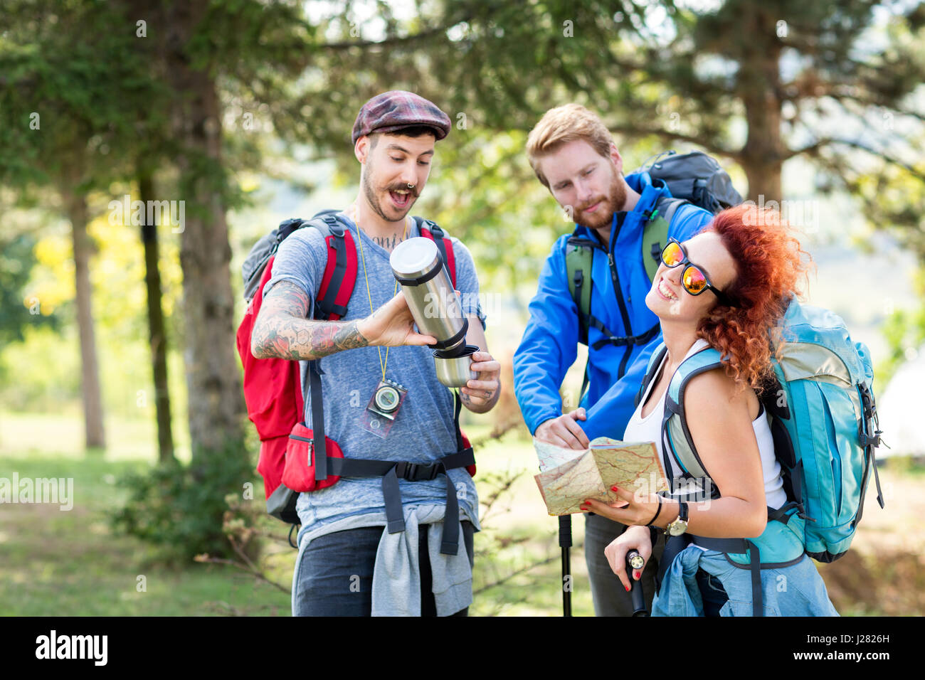 Group of mountaineering in forest with backpack, thermos, map and hiking sticks in green forest Stock Photo