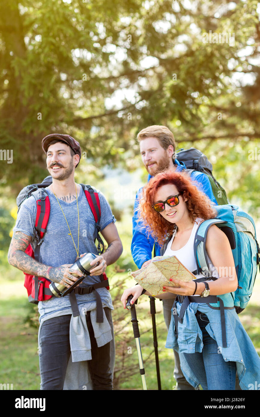 Group of hikers in forest with backpack, thermos, map and hiking sticks in green forest Stock Photo