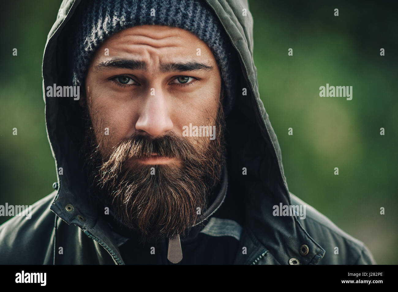 Outdor porttrait of a handsome brutal bearded man with dark beard and mustache dressed in winter clothes, covered with frost. Man wear coat hat and ho Stock Photo