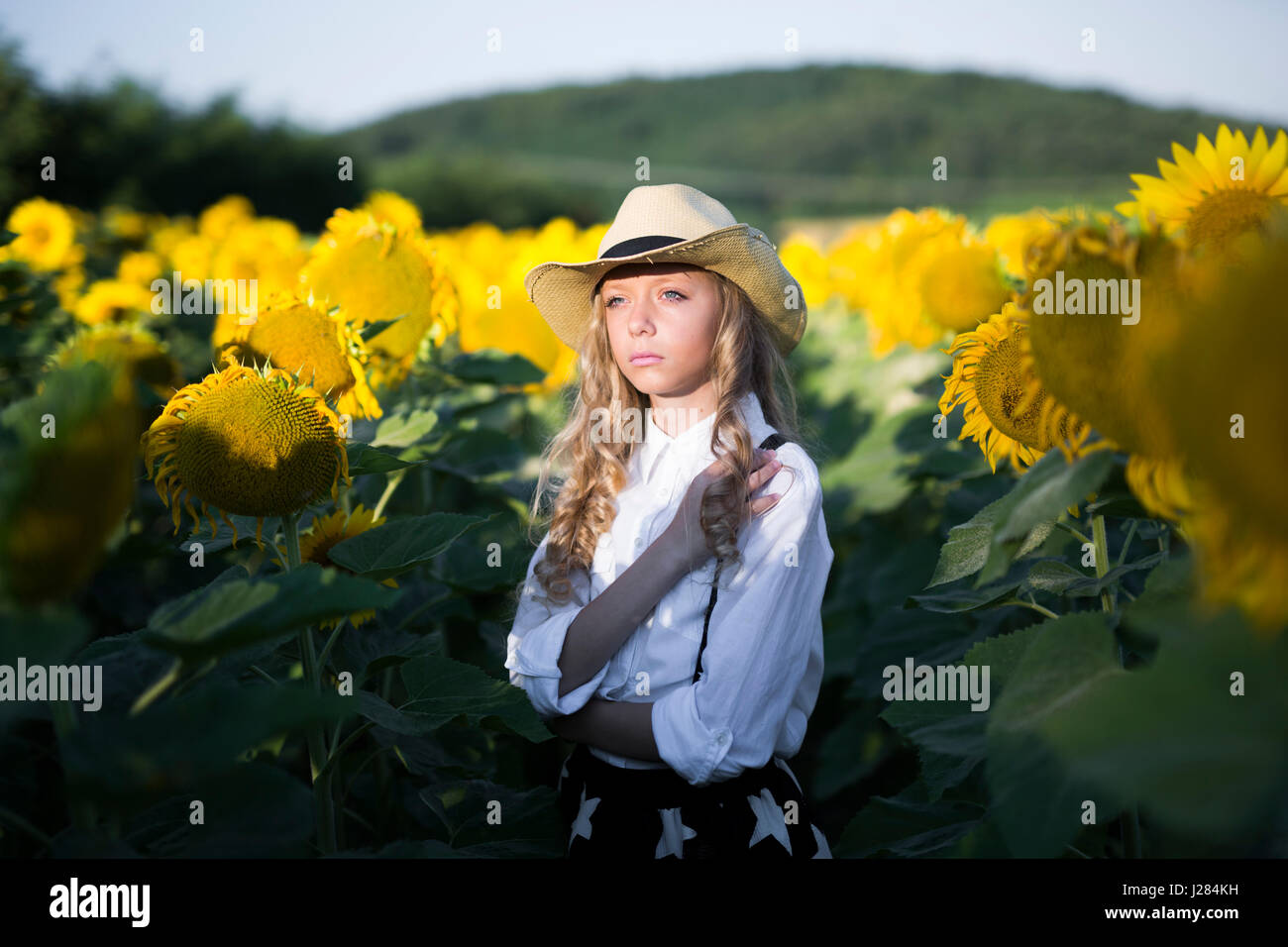 Thoughtful teenage girl in cowboy hat standing in sunflower field Stock ...