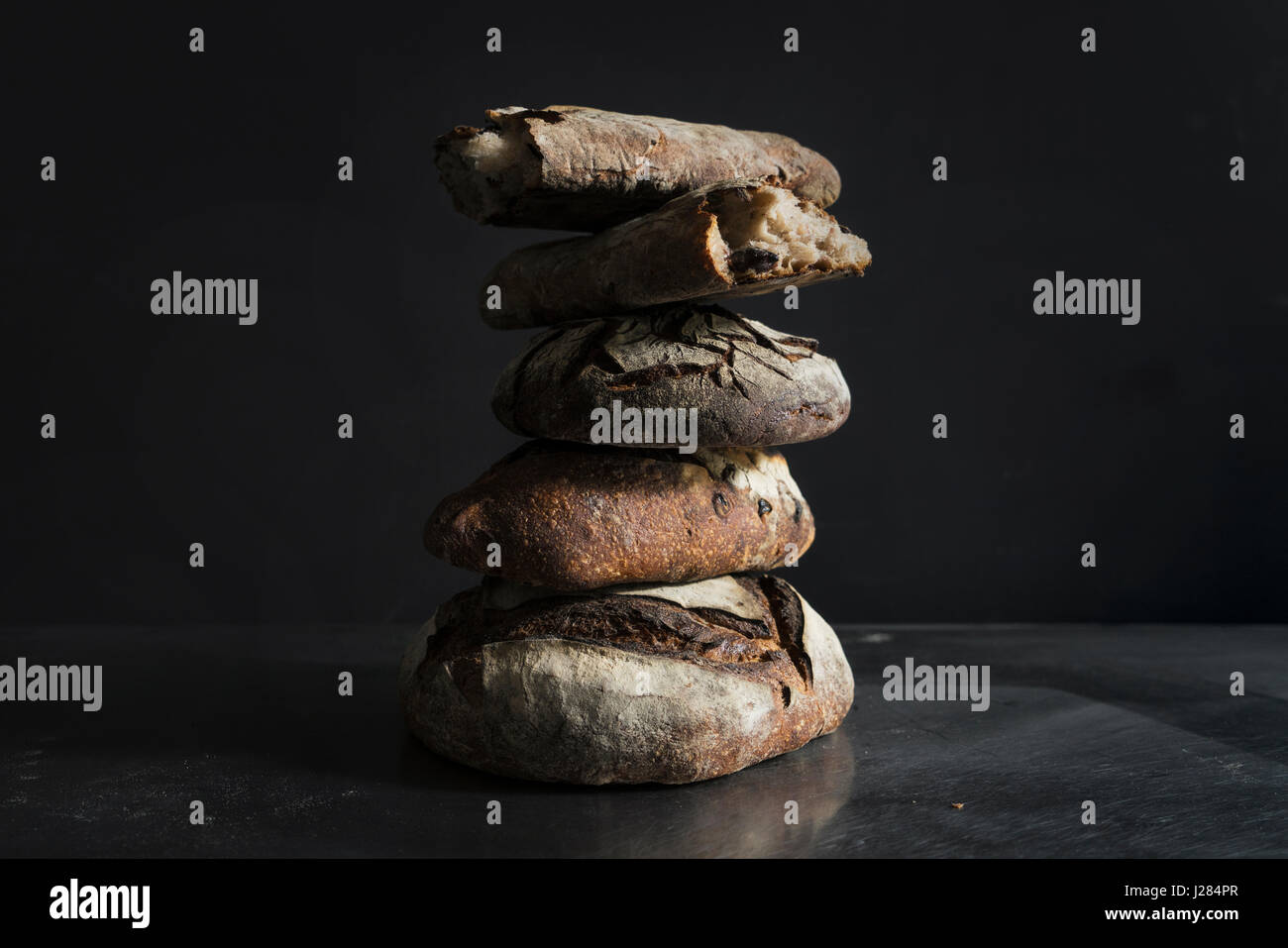 Stack of sourdough bread on table against black background Stock Photo