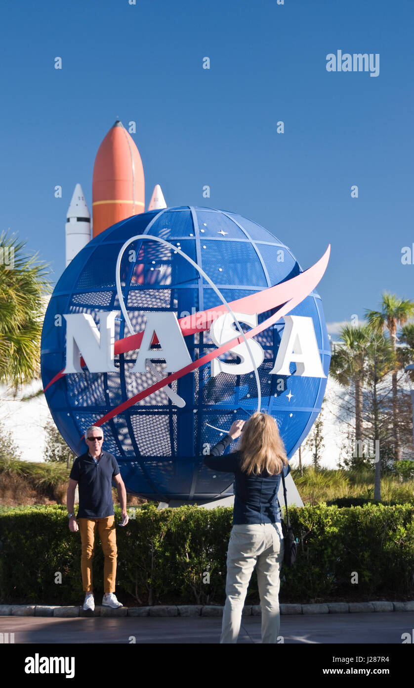 Tourists make photos next to a large NASA logo outside the Visitor Complex at NASA's Kennedy Space Center, Florida. Stock Photo
