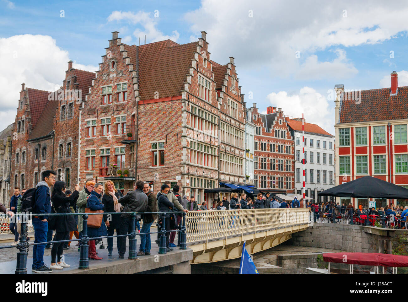View of tourists and the streets Graslei (Grass Quay), Vleeshuistragel and Hooiaard with their medieval buildings under a blue sky. Ghent, Belgium. Stock Photo