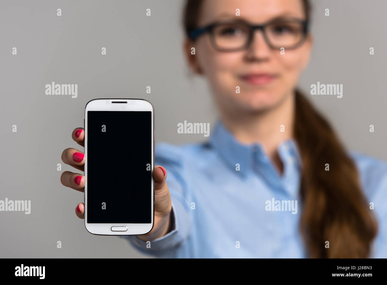 Business woman holding white mobile phone with empty black screen Stock Photo