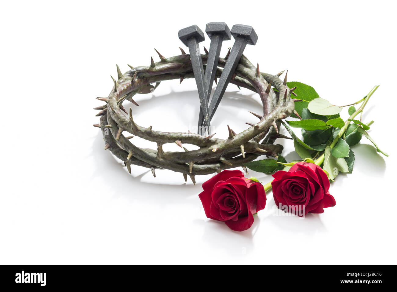 Jesus Christ crown of thorns, nails and two roses on a white background. Stock Photo