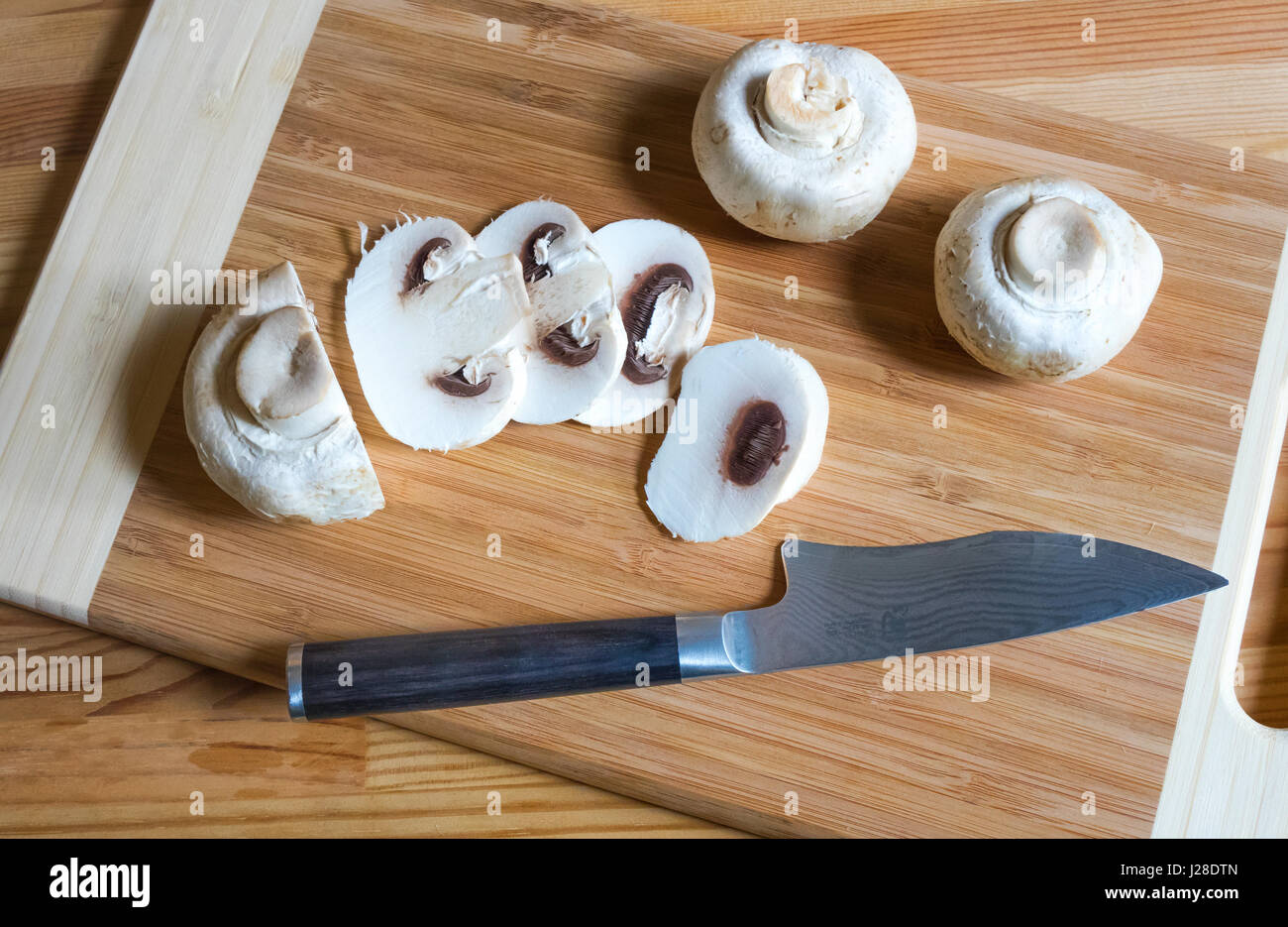 Button mushrooms and high end paring knife and wooden cutting board Stock Photo