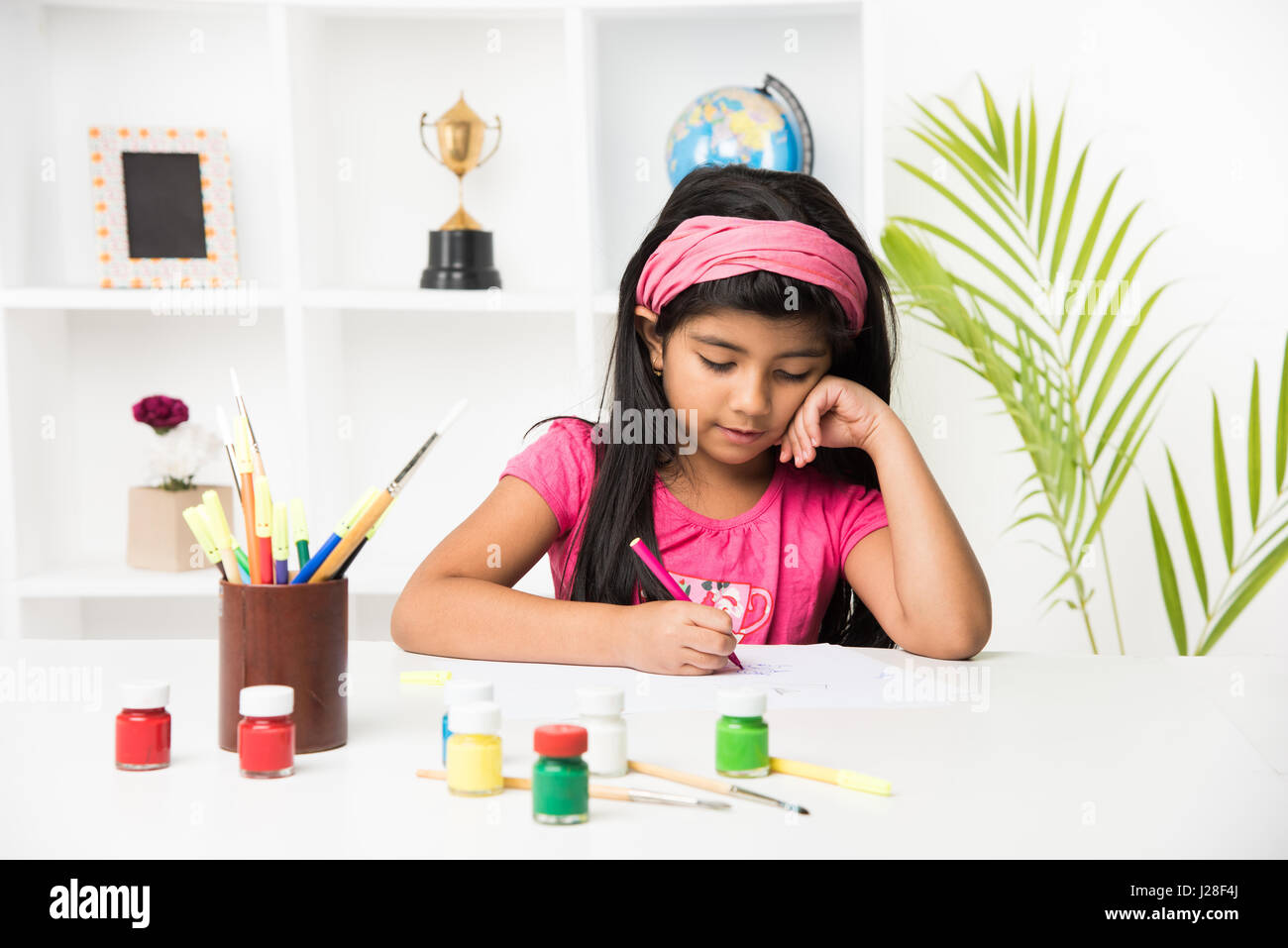 Kids and fun concept - cute Little asian or Indian girl drawing or colouring or painting at home Stock Photo